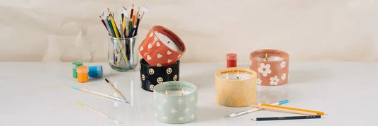 St. Jude collection of candles on a white table top with colored pencils and paint brushes