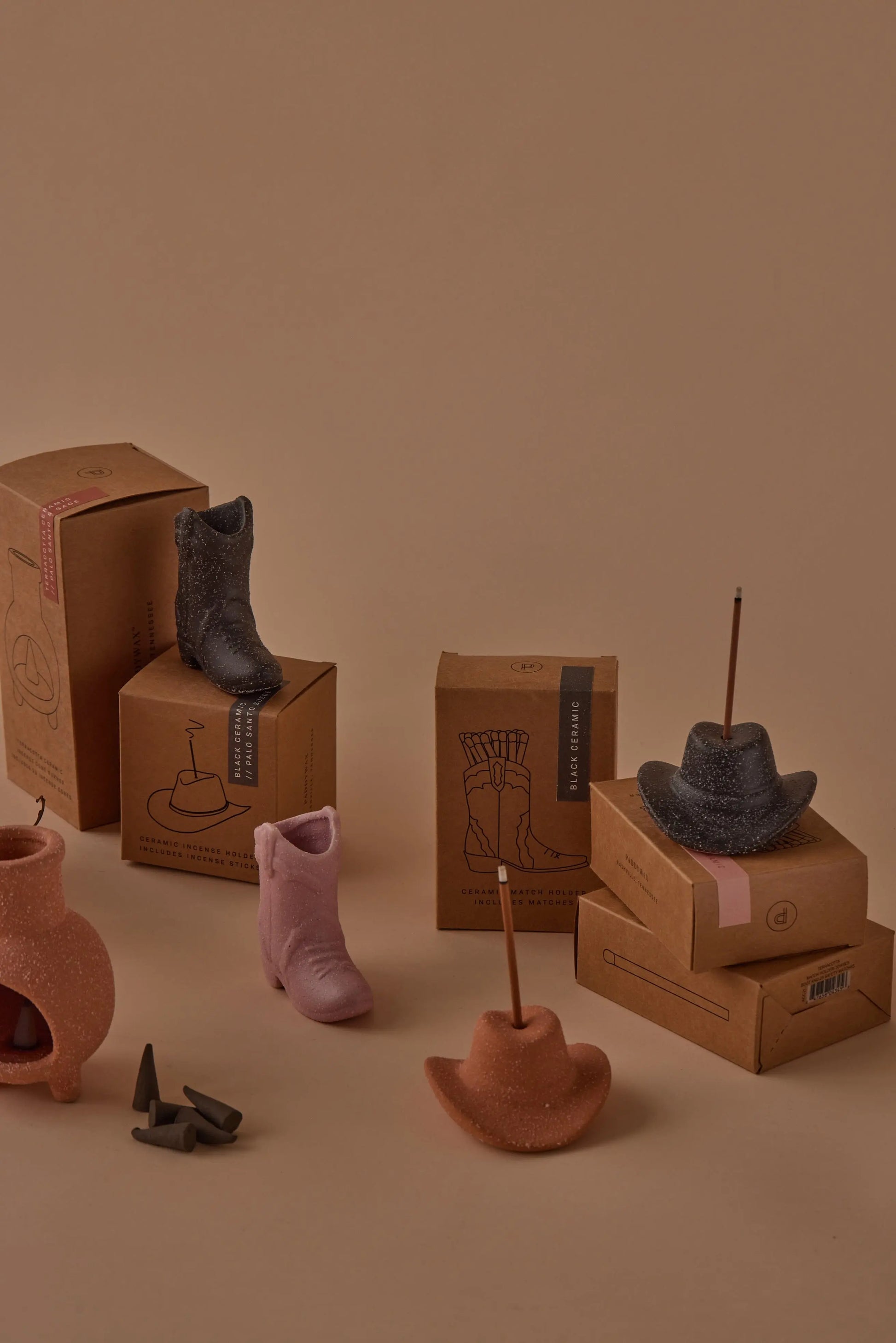 The Cowboy Hat Incense Holder - Black is displayed on and around cardboard boxes against a beige background, capturing the distinctive charm of Nashville.