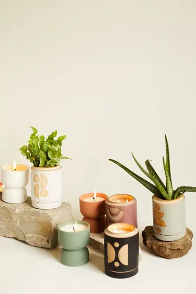 A calming display features six Form 6oz. Mint Matte Hourglass Ceramic candles in Ocean Rose & Bay, two small potted plants, and two rocks on a neutral background for a fresh, natural fragrance.