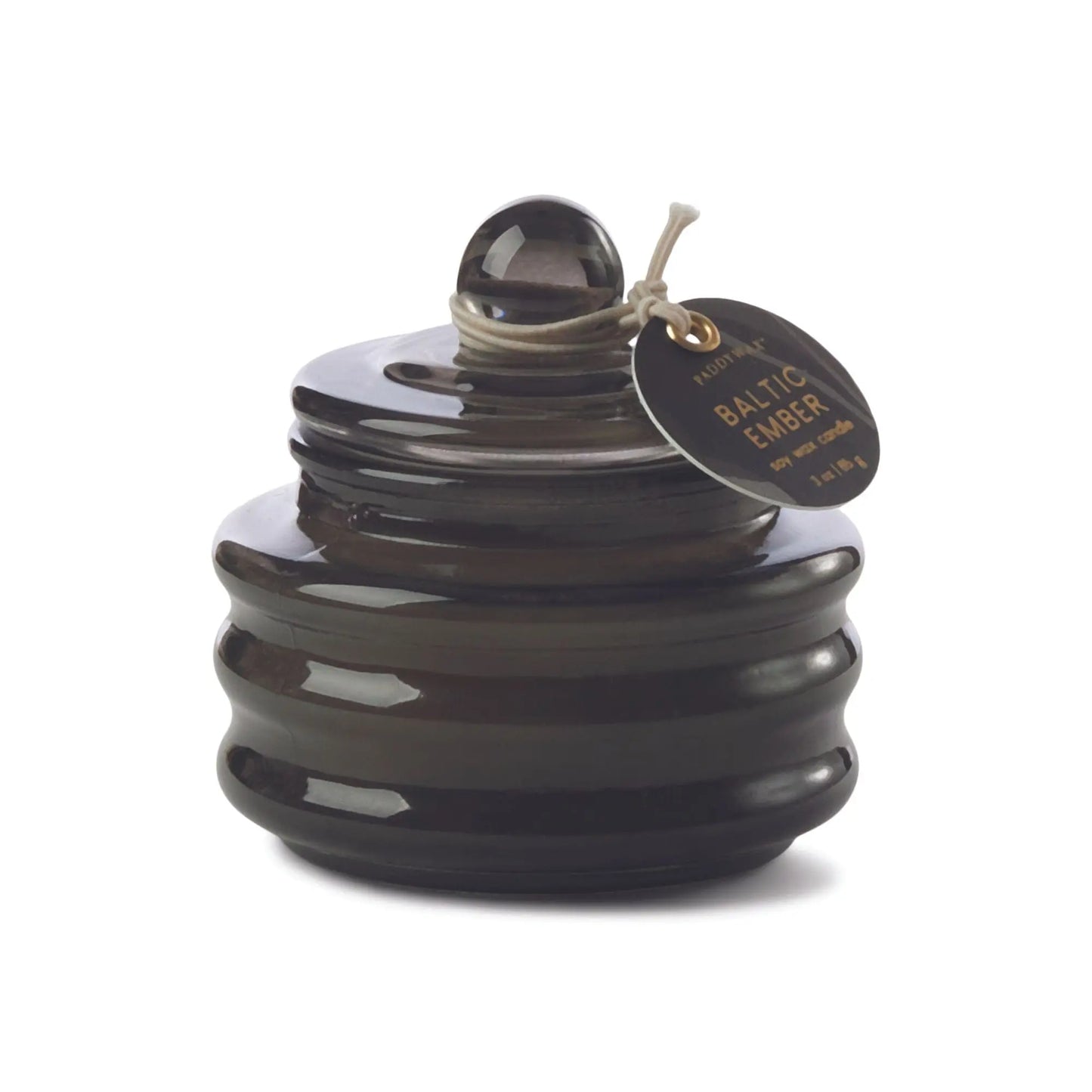 The Beam 3oz Glass Candle - Baltic Ember comes in a dark glass jar with a round lid and tag, filling your space with luxurious scents and casting a soft, ambient light.