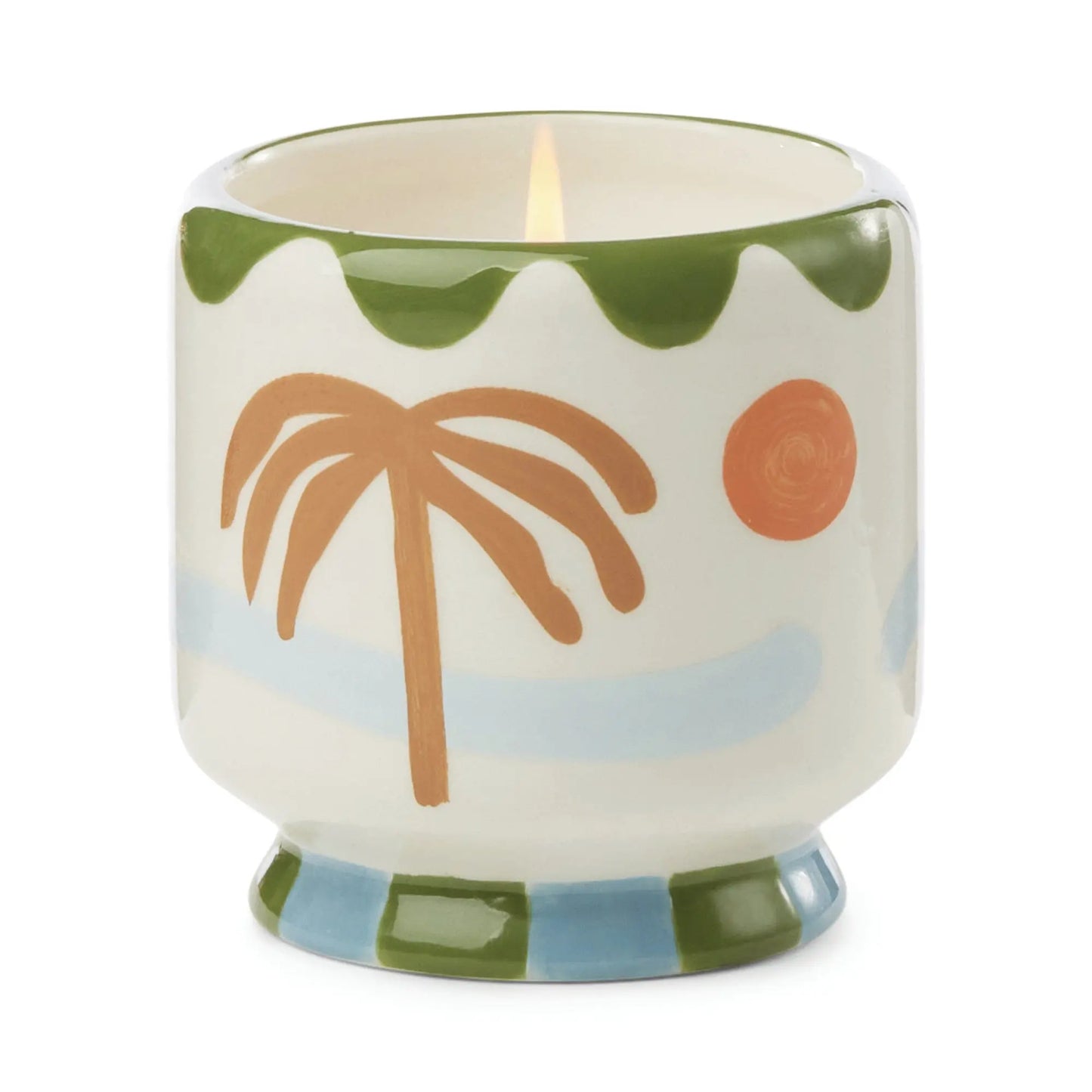 The A Dopo Palm Tree Candle - Lush Palms features a lit ceramic holder adorned with a palm tree, sun, blue waves, and green details—ideal for fans of Mediterranean candles and artistic decor.