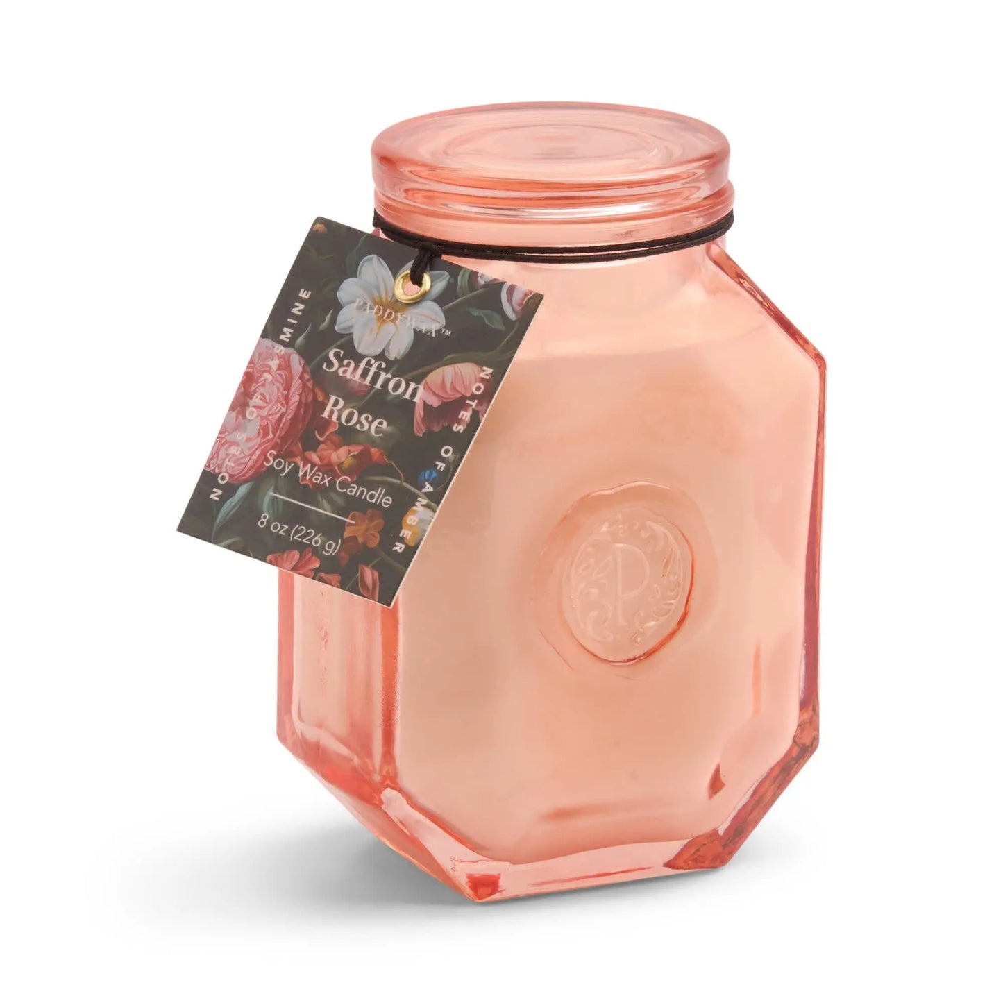 The Botanica Candle - Saffron Rose features a pink glass jar and soy wax, adorned with a decorative tag—an elegant choice from the Luxurious Botanica Collection for candle and diffuser enthusiasts.