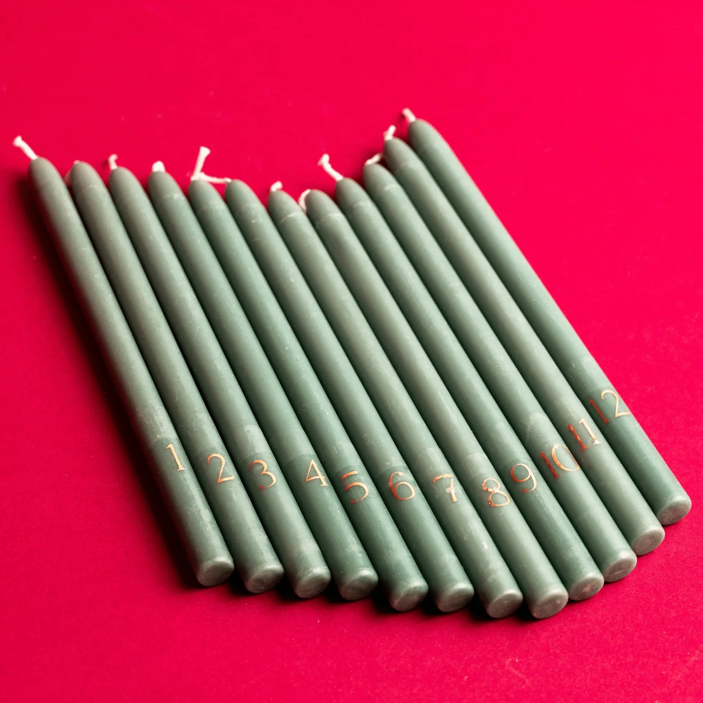 Taper 12 Days of Christmas Countdown Candles on a red table