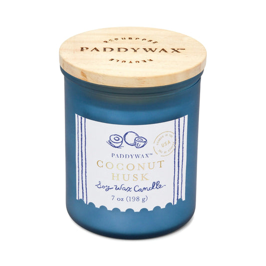 The Coastal 7oz Candle - Coconut Husk features a blue glass jar with a wooden lid, inspired by sea glass and fresh coastal breezes, and is part of Paddywaxs Coastal Candle Collection.