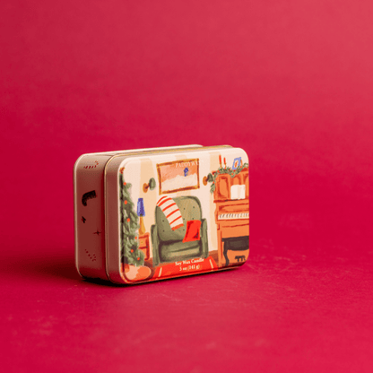 On a red background, 5 oz holiday tin with custom artwork; lid shows family room with piano and decorated tree 