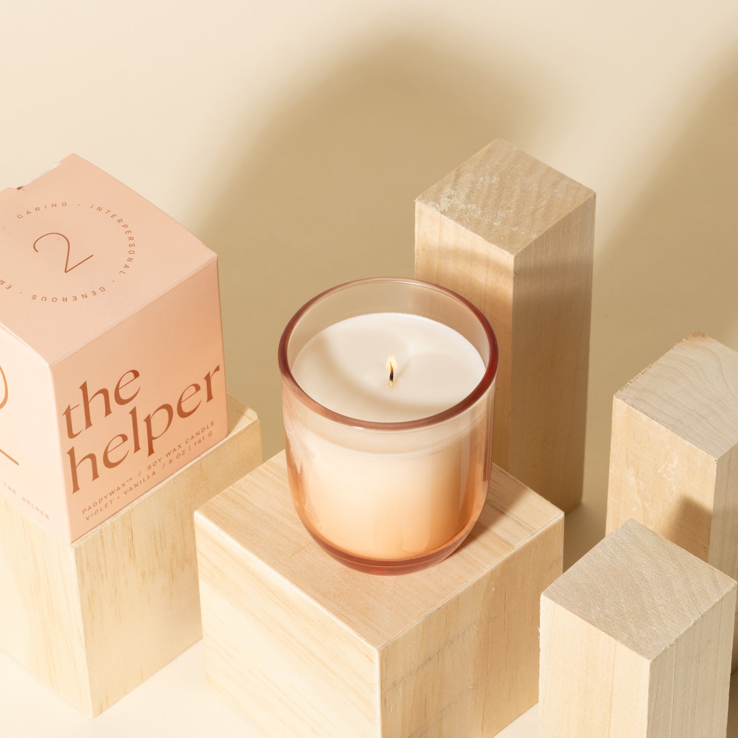 Pink candle with white soy wax burning with pink packaging near candle - Enneagram Candle Paddywax for Enneagram 2 the helper