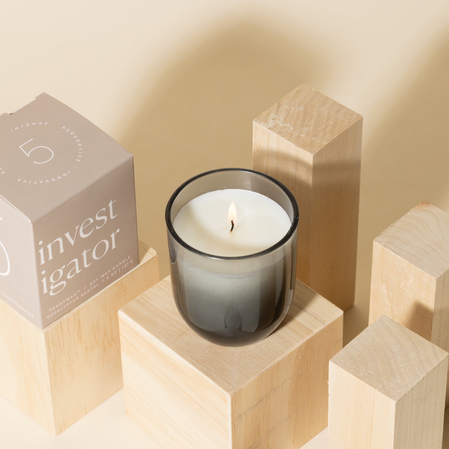 Grey candle with white soy wax burning with grey packaging near candle - Enneagram Candle Paddywax for Enneagram 5 the investigator