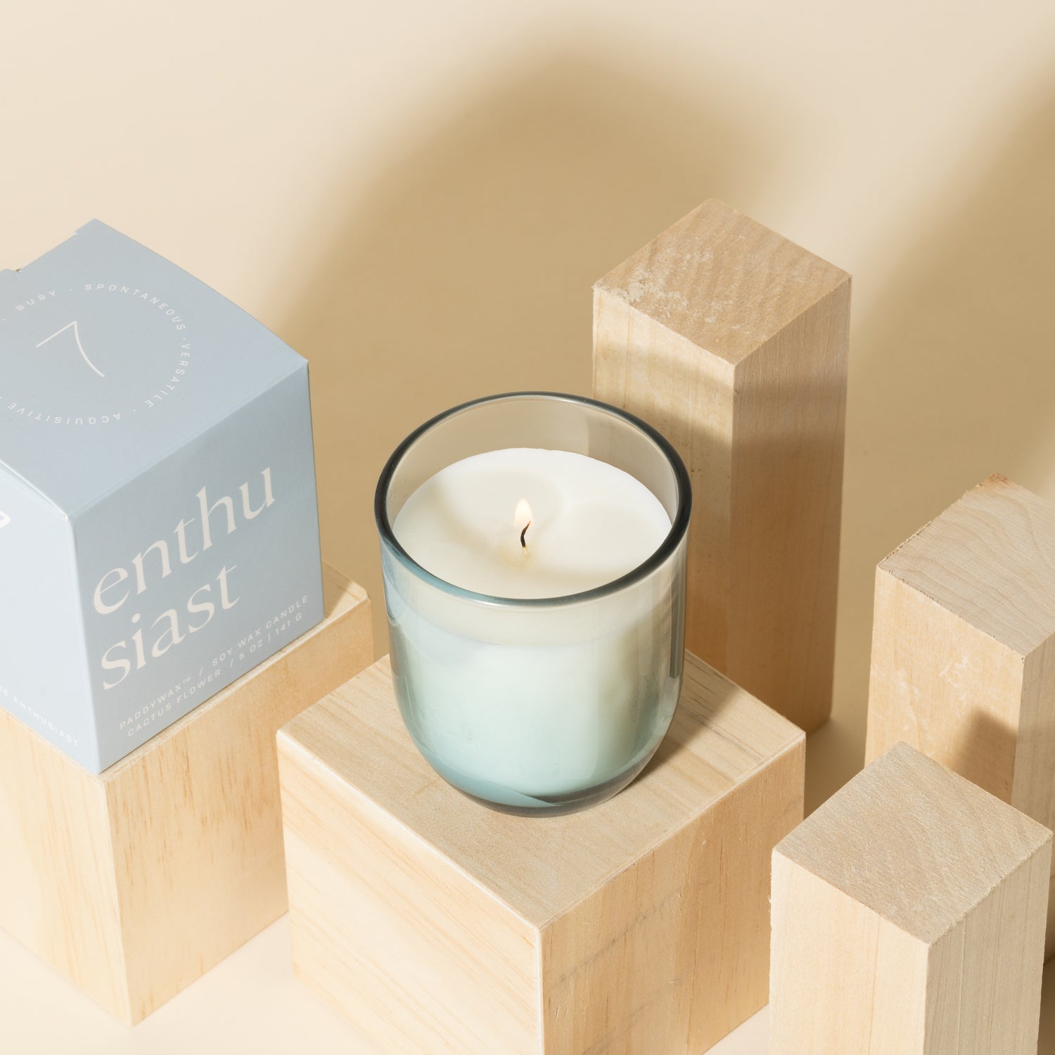 Blue candle with white soy wax burning with blue packaging near candle - Enneagram Candle Paddywax for Enneagram 7 the enthusiast