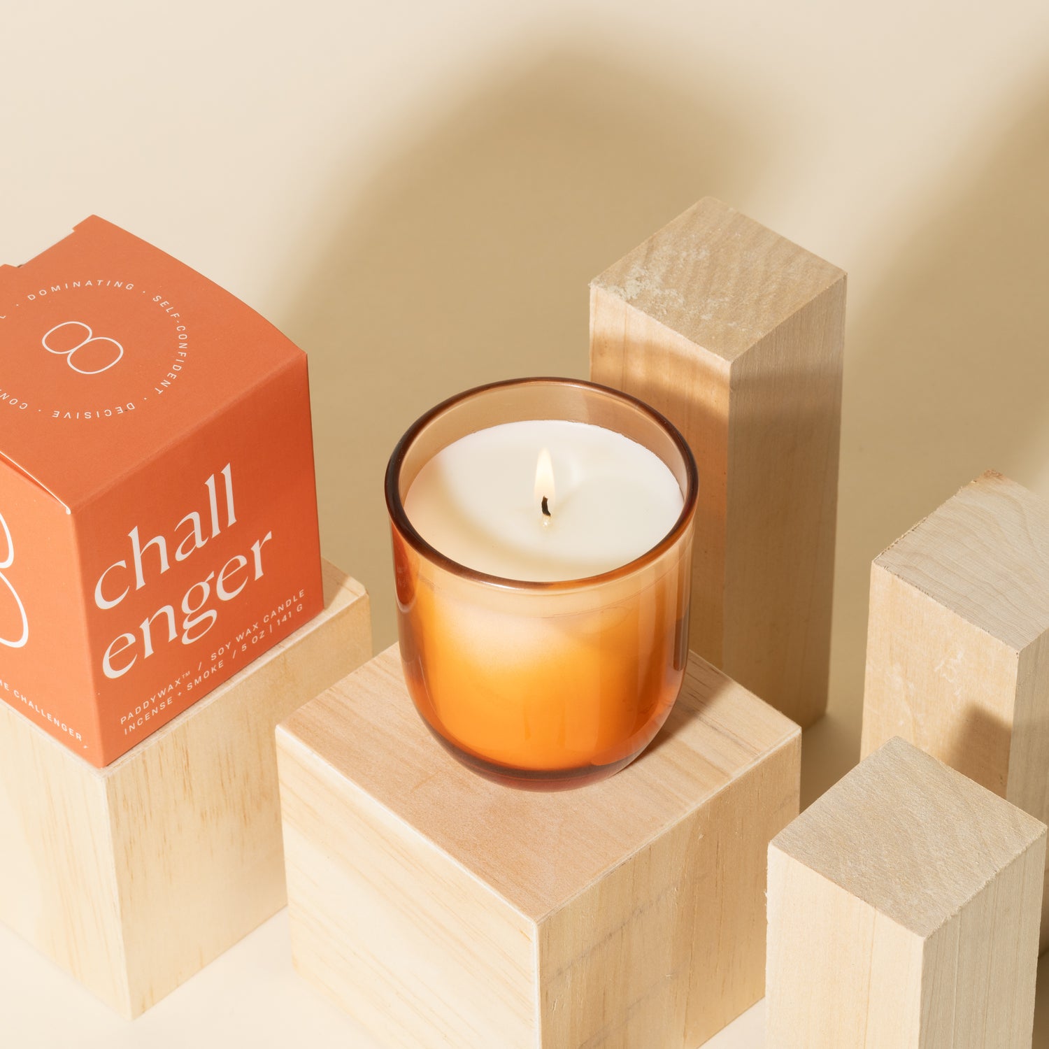 Orange candle with white soy wax burning with orange packaging near candle - Enneagram Candle Paddywax for Enneagram 8 the challenger