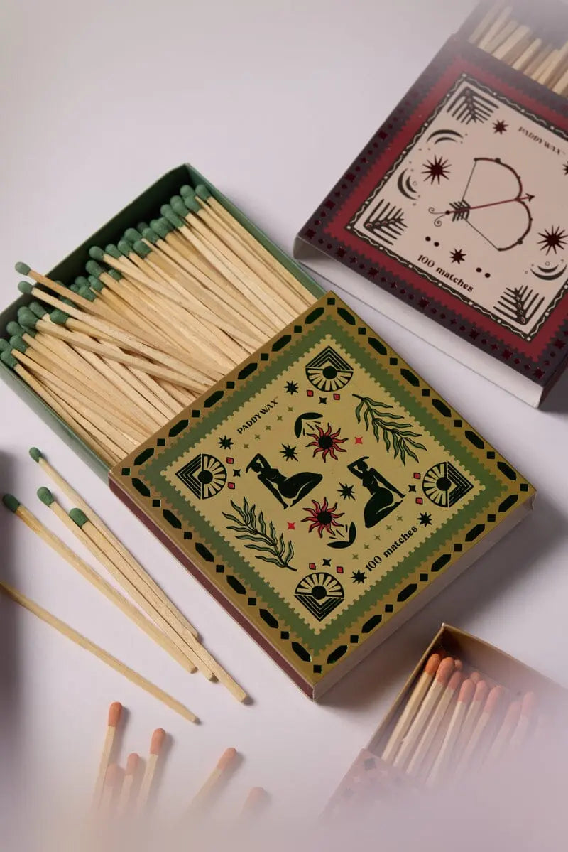 The Jumbo Boxed Matches - Femme features three decorative matchboxes, one open to reveal green-tipped matches. Each lid displays stylish illustrations of animals, plants, and geometric patterns—perfect as a charming candle accessory.