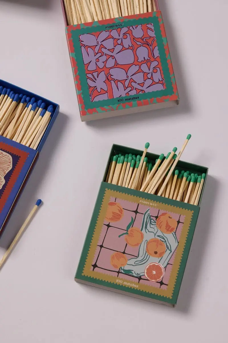 A Jumbo Boxed Matches - Oranges is displayed on a white surface. The box features a colorful, patterned design with decorative matches—perfect for pairing with your favorite Paddywax candle.