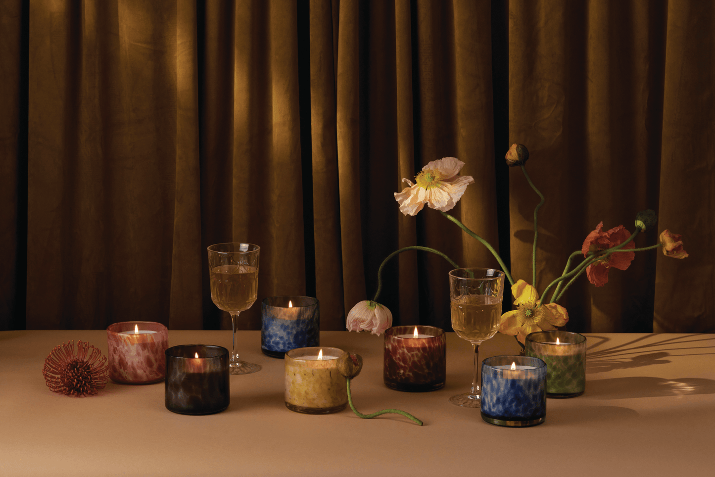 Candles from the Luxe collection with a brown curtain in the background.