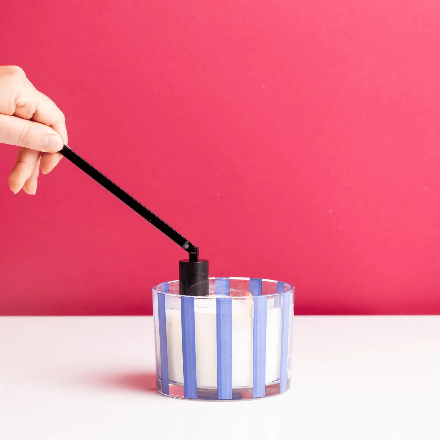 Matte Black Candle Snuffer snuffing candle on white table with red background