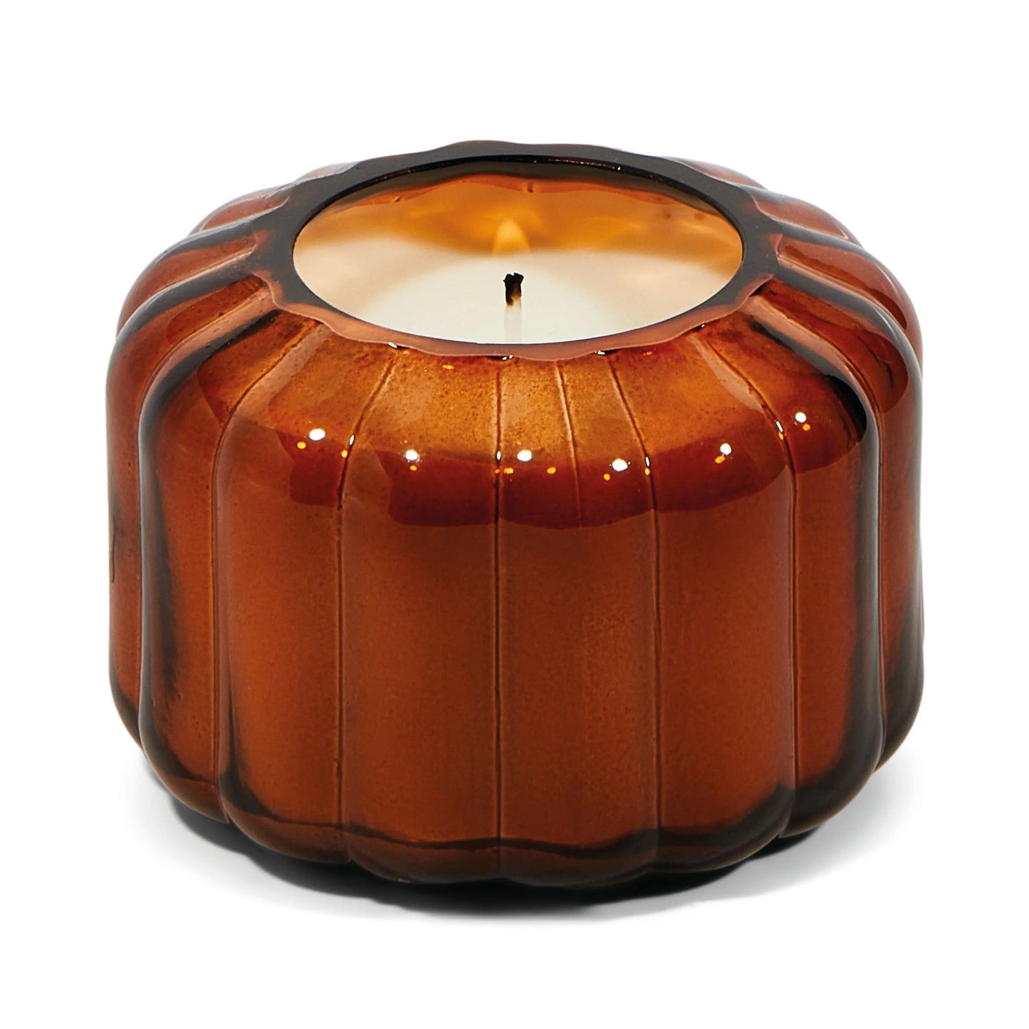 A single white candle in the Ripple Candle - Tobacco Patchouli, a Mini Ripple round ribbed colored glass holder with a scalloped edge, inspired by vintage glass vessels.