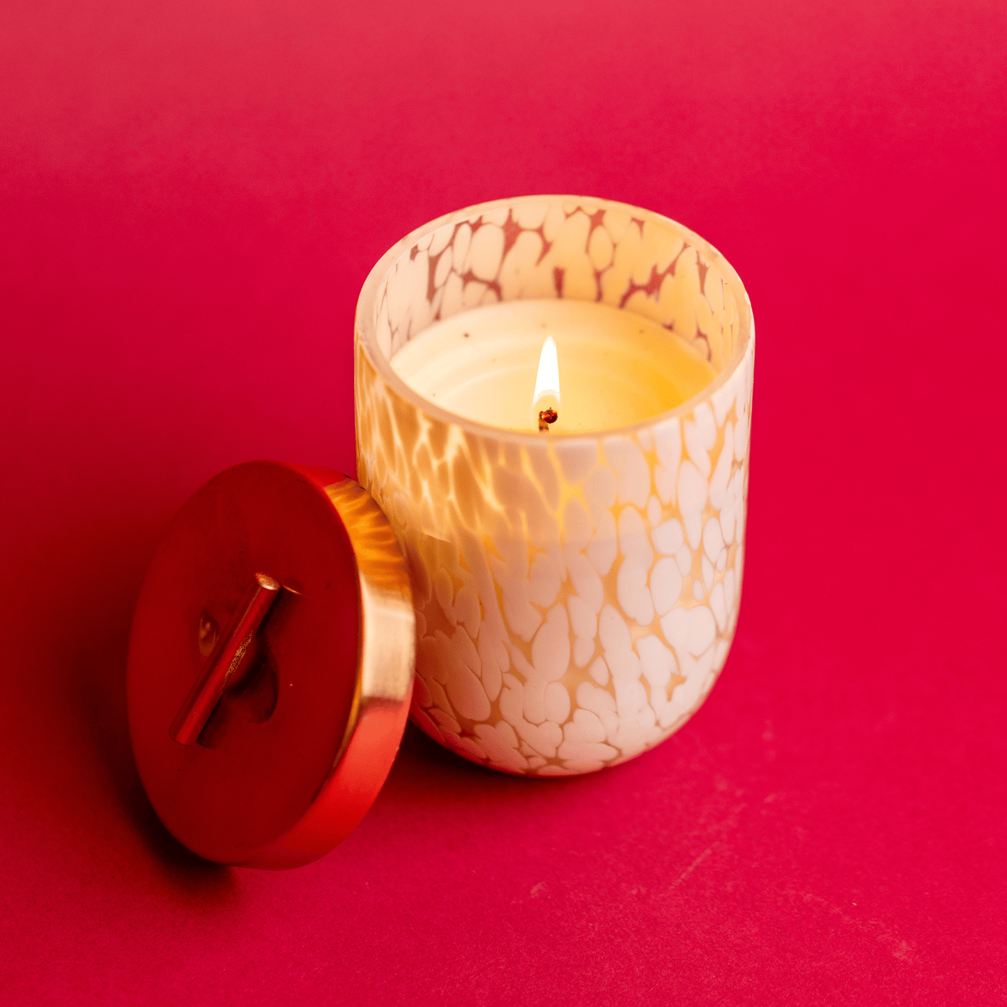 White Blown Glass Candle and brass lid on red table
