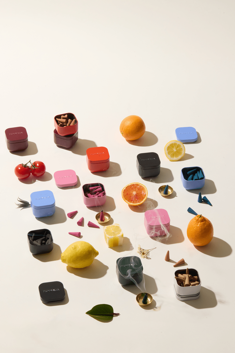 Colorful incense tins with small fruits on a light background
