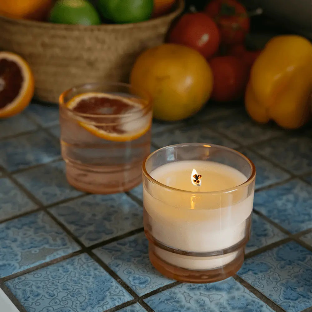 7 oz Al Fresco candle with a light pink vessel pictured next to glass of water with grapefruit in it.
