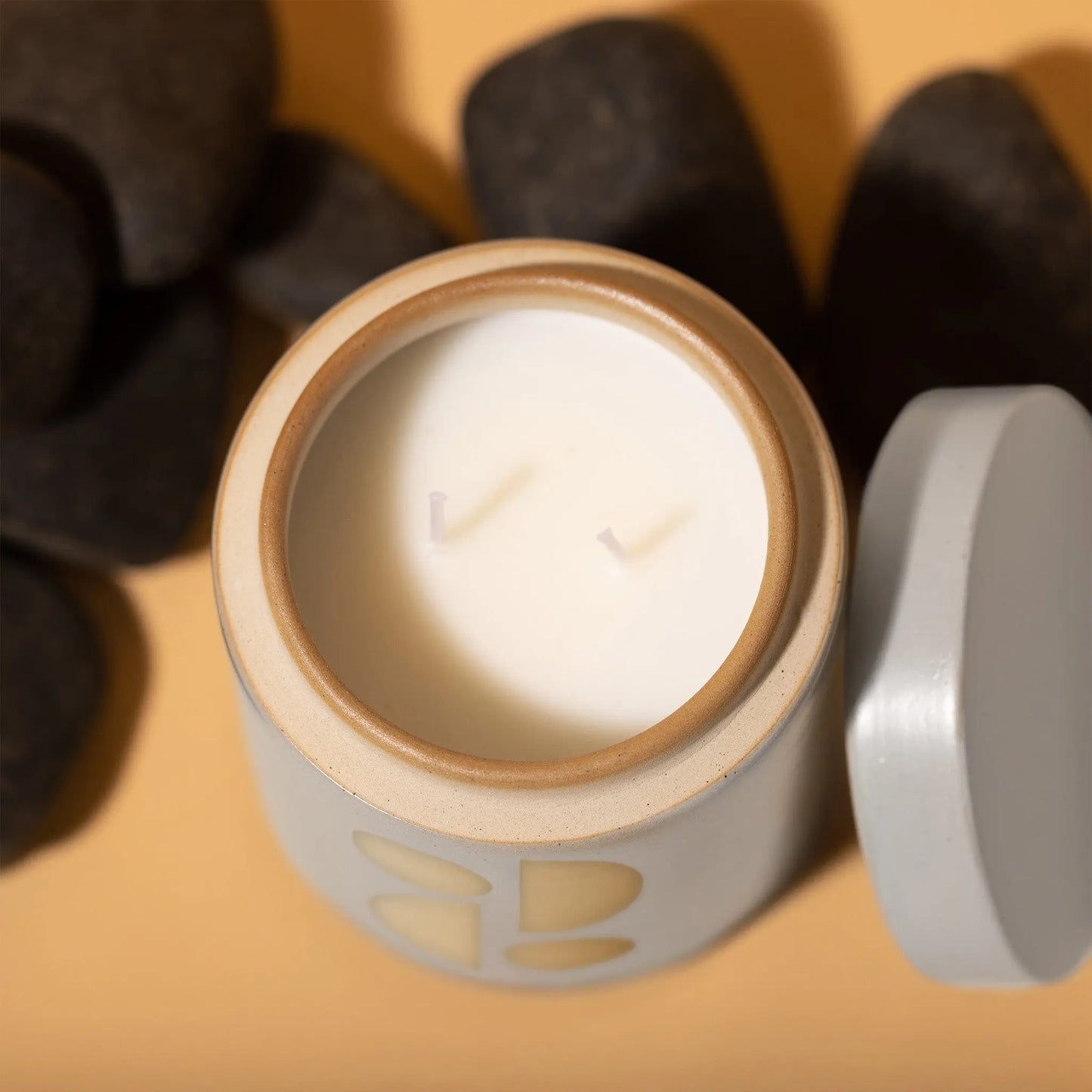 12 oz white cylindrical ceramic vessel with ceramic lid; white wax and two cotton wicks; reflected beige mirrored semi-circle design on the side