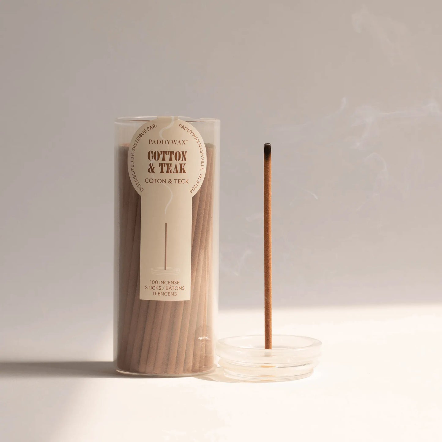 Clear glass cylinder holding 100 incense sticks for flameless fragrance; pictured next to an incense stick being burned