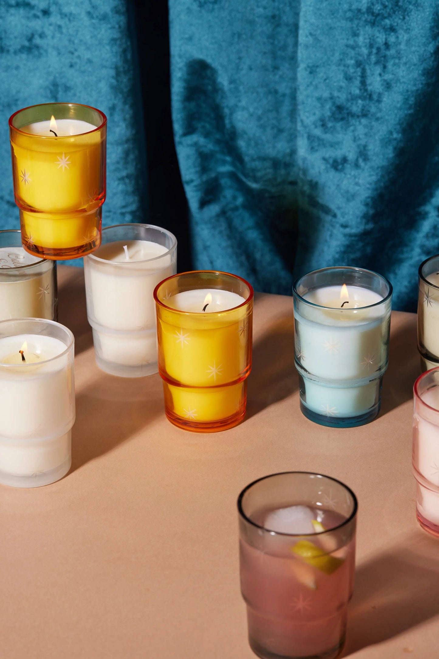 9 Candles showing in the picture - 6 different varieties for purchase. Candles are shown on a table with a dark blue curtain behind them