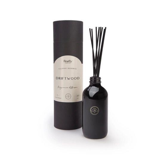 The Black Diffuser - Driftwood features a black bottle with fragrance sticks and a matching cylindrical container, providing a luxurious, flameless scent experience.