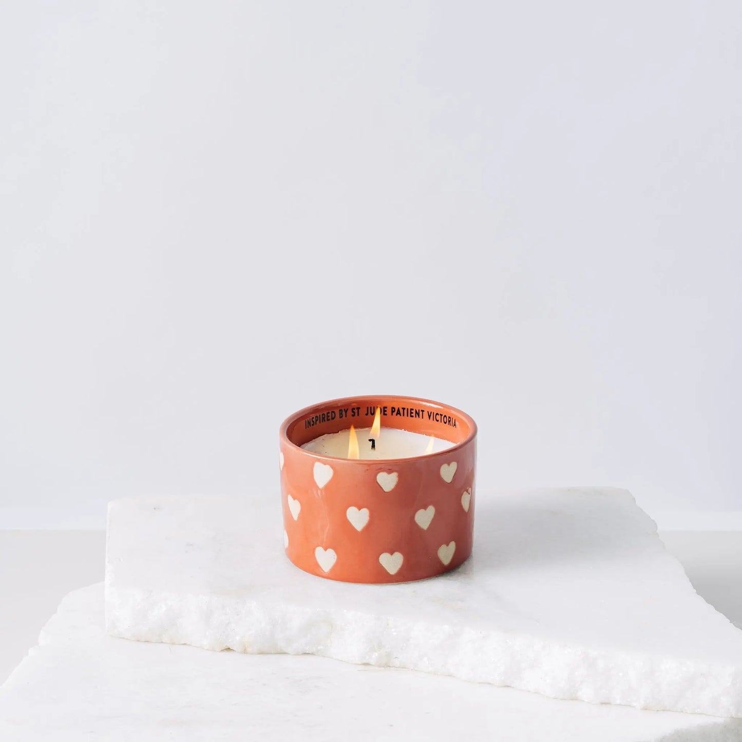 Red ceramic candle with hearts and white soy wax center with three wicks burning
