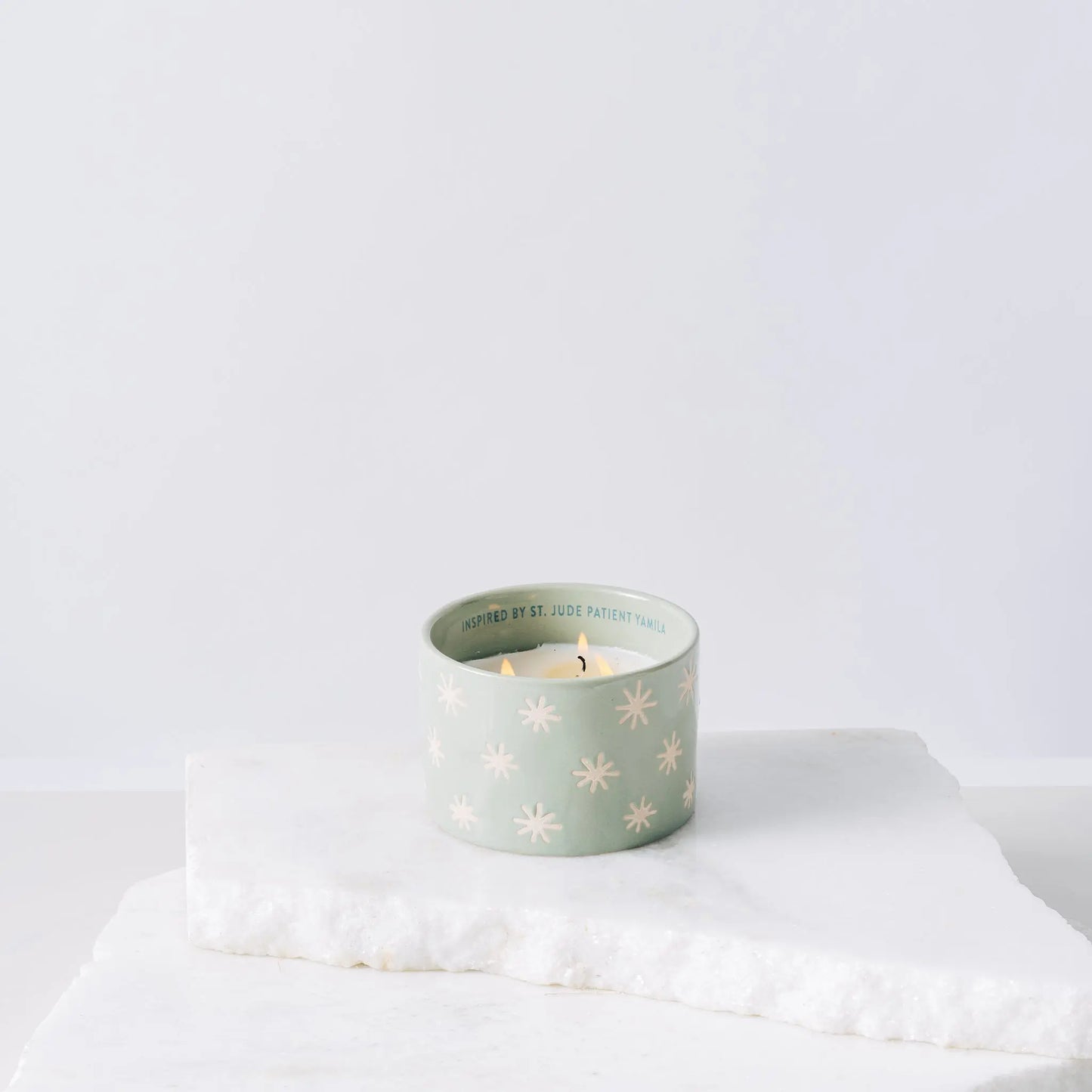 Green ceramic candle with sparkles and white soy wax center with three wicks burning