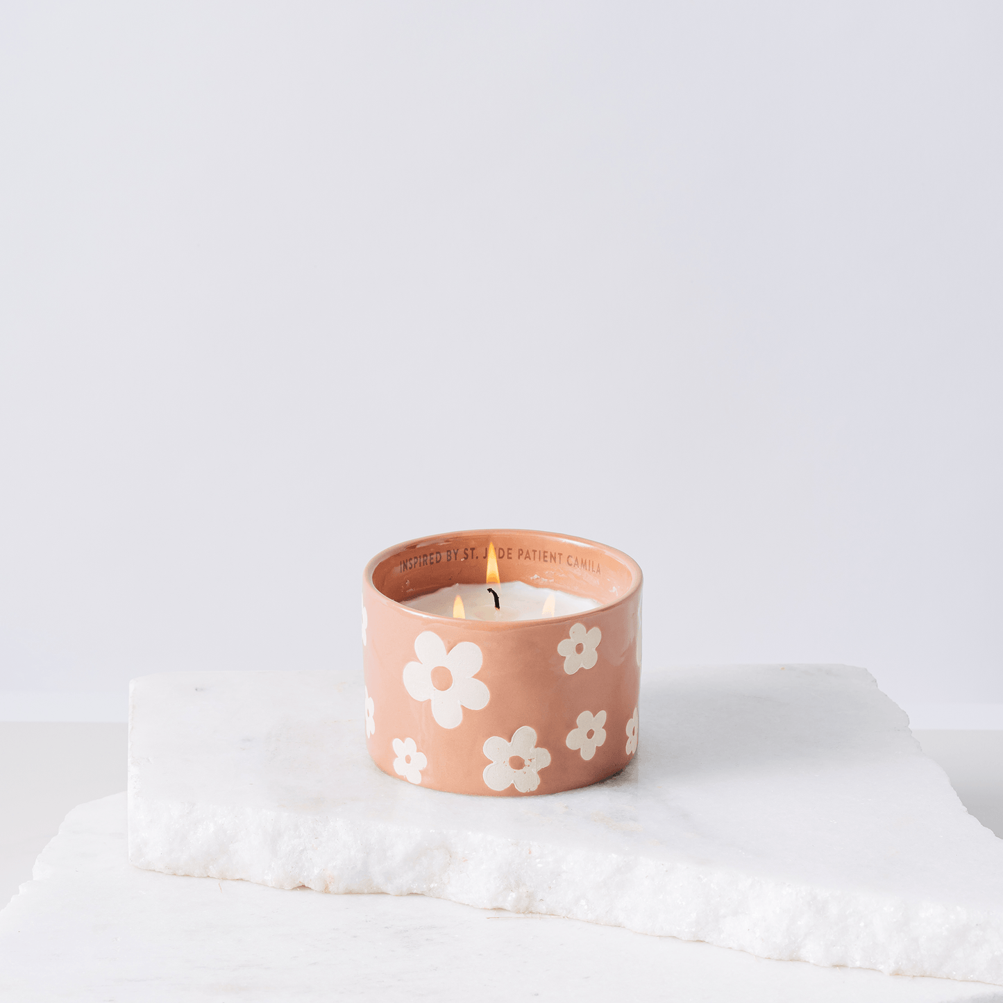 Pink ceramic candle with flowers and white soy wax center with three wicks burning 