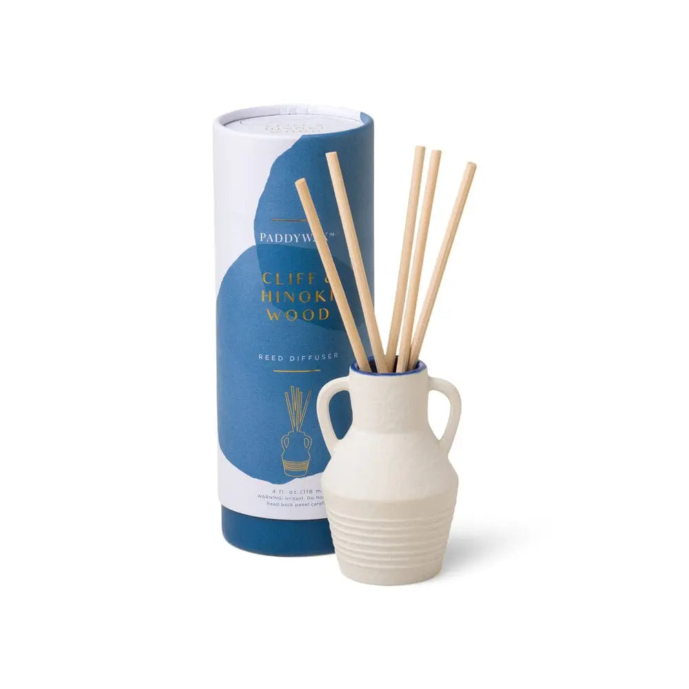 The Santorini 4 fl oz. Diffuser - Cliff & Hinoki Wood sits beside its cylindrical packaging, filling the air with a fresh scent inspired by the Aegean Sea.