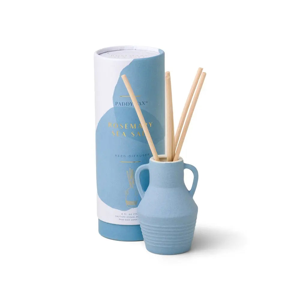 The Santorini 4 fl oz. Diffuser - Rosemary Sea Salt features a blue ceramic vessel and natural wooden sticks, presented in matching cylindrical packaging—capturing the fresh, coastal spirit of the Aegean Sea.