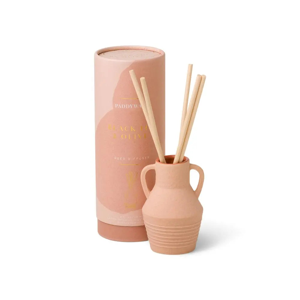 The Santorini 4 fl oz. Diffuser - Black Fig & Olive features a ceramic vessel with wooden sticks, displayed in front of its cylindrical packaging—evoking the breezy scents of the Aegean Sea.