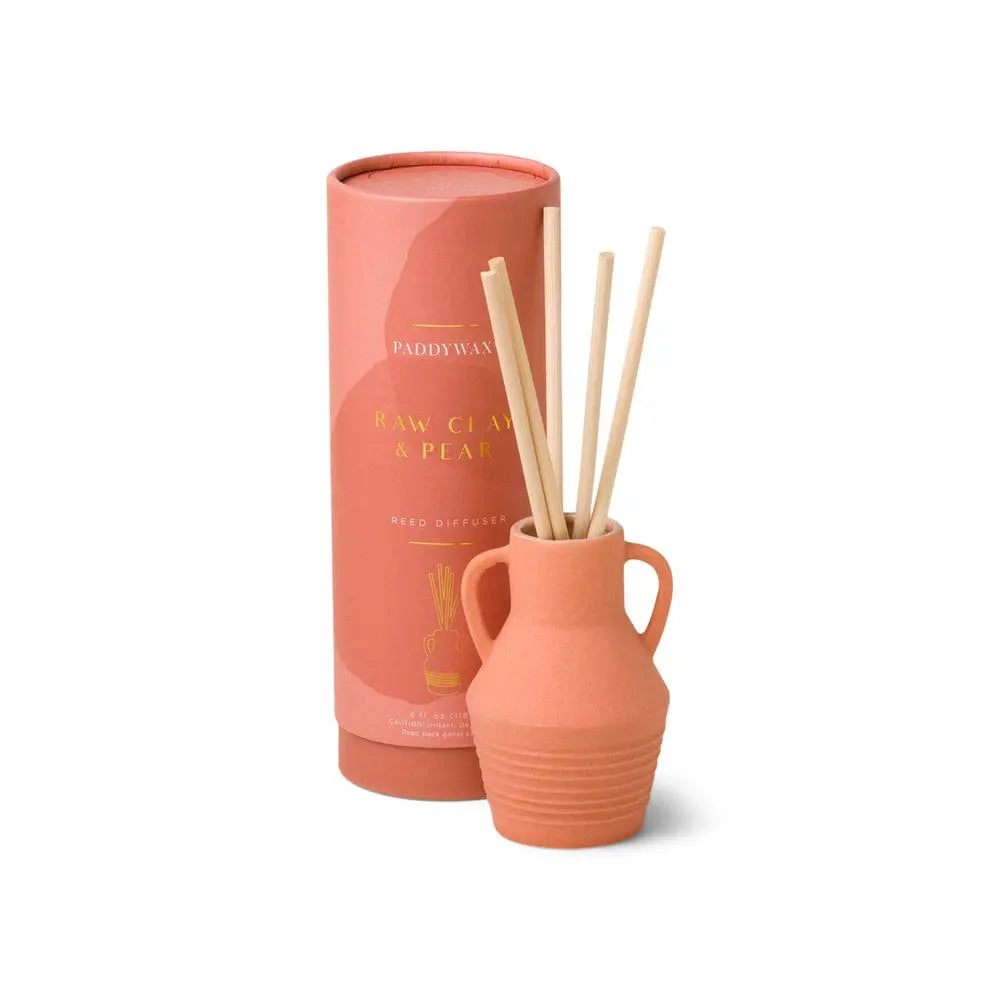 The Santorini 4 fl oz. Diffuser – Raw Clay & Pear, with wooden sticks and a pink cylindrical box, brings a subtle fragrance and decorative touch to your space.