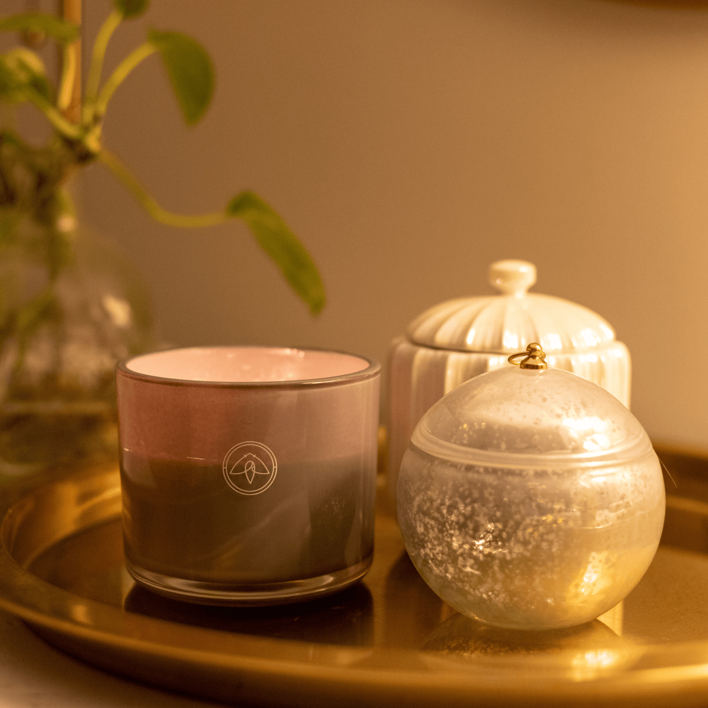 10oz Serenity two wick candle on gold metal tray with home decor, planter int he background