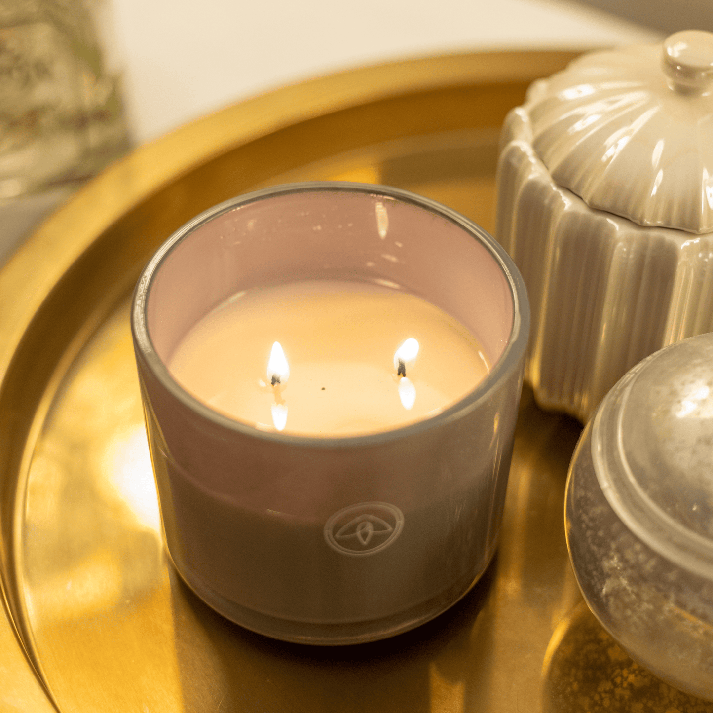 overheard shot of 10oz Serenity two wick candle on gold metal tray next to home decor