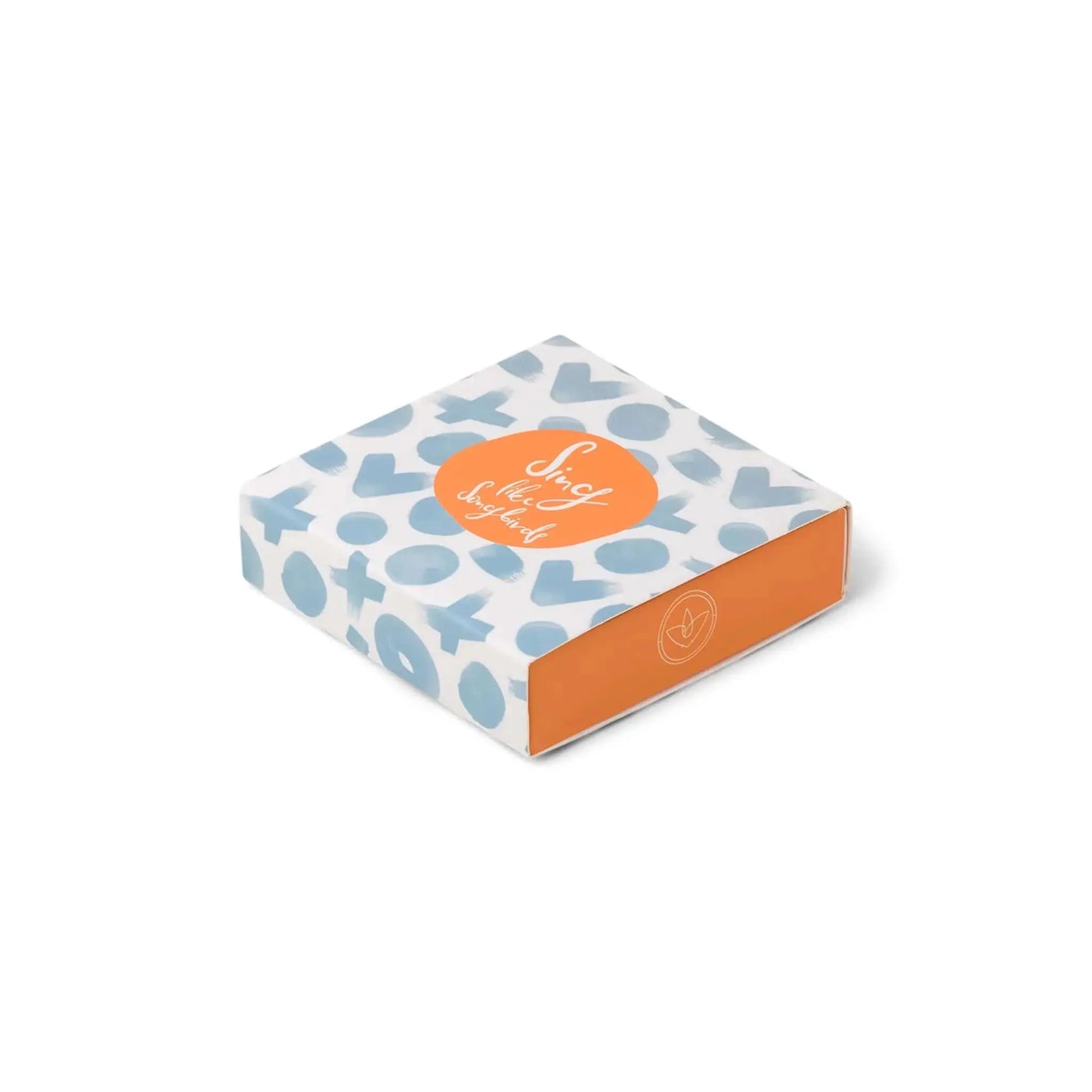 A square box with a blue X and O pattern, orange sides, and an orange circle label on top that reads “Nice choice, Self-Love Supply Kit”—a perfect companion to your candle collection or Terrace Matches - Sing Like Songbirds.