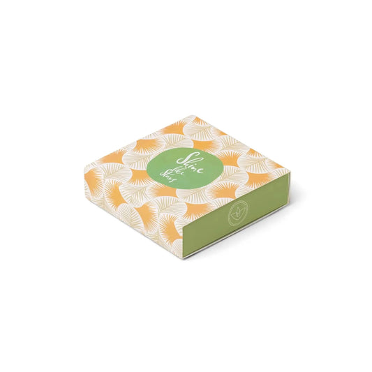 A rectangular gift box with a green side and an orange top with white leaves, labeled Shine, Self-Care Box in a green circle—perfect to pair with the Terrace Matches - Shine Like Stars or your favorite candle collection.