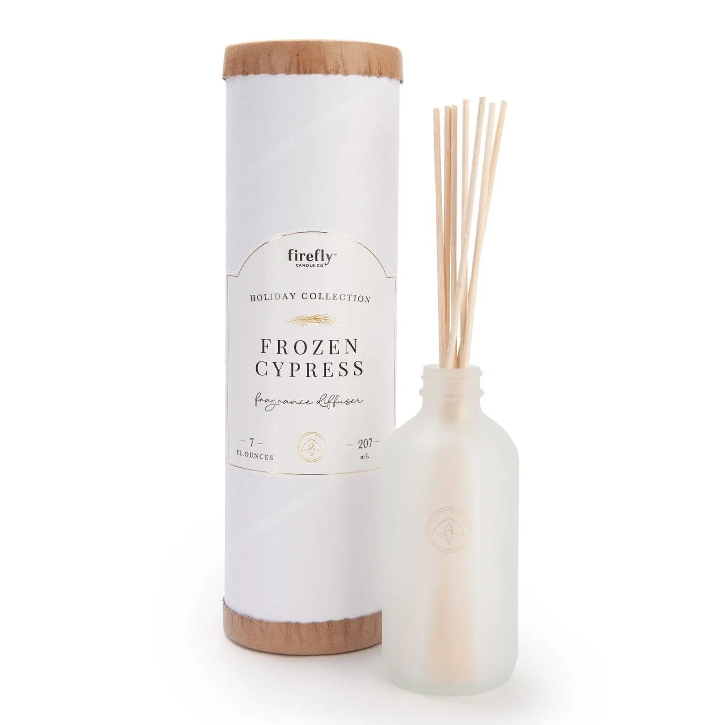 The Holiday Reed Diffuser - Frozen Cypress stands beside a frosted glass bottle with wooden reeds, providing a flameless fragrance ideal for holiday gifting.