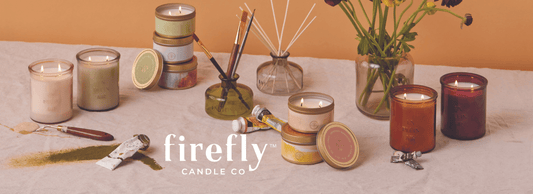 white Firefly Candle Co logo with en plein air candle collection on table top with paint brushes