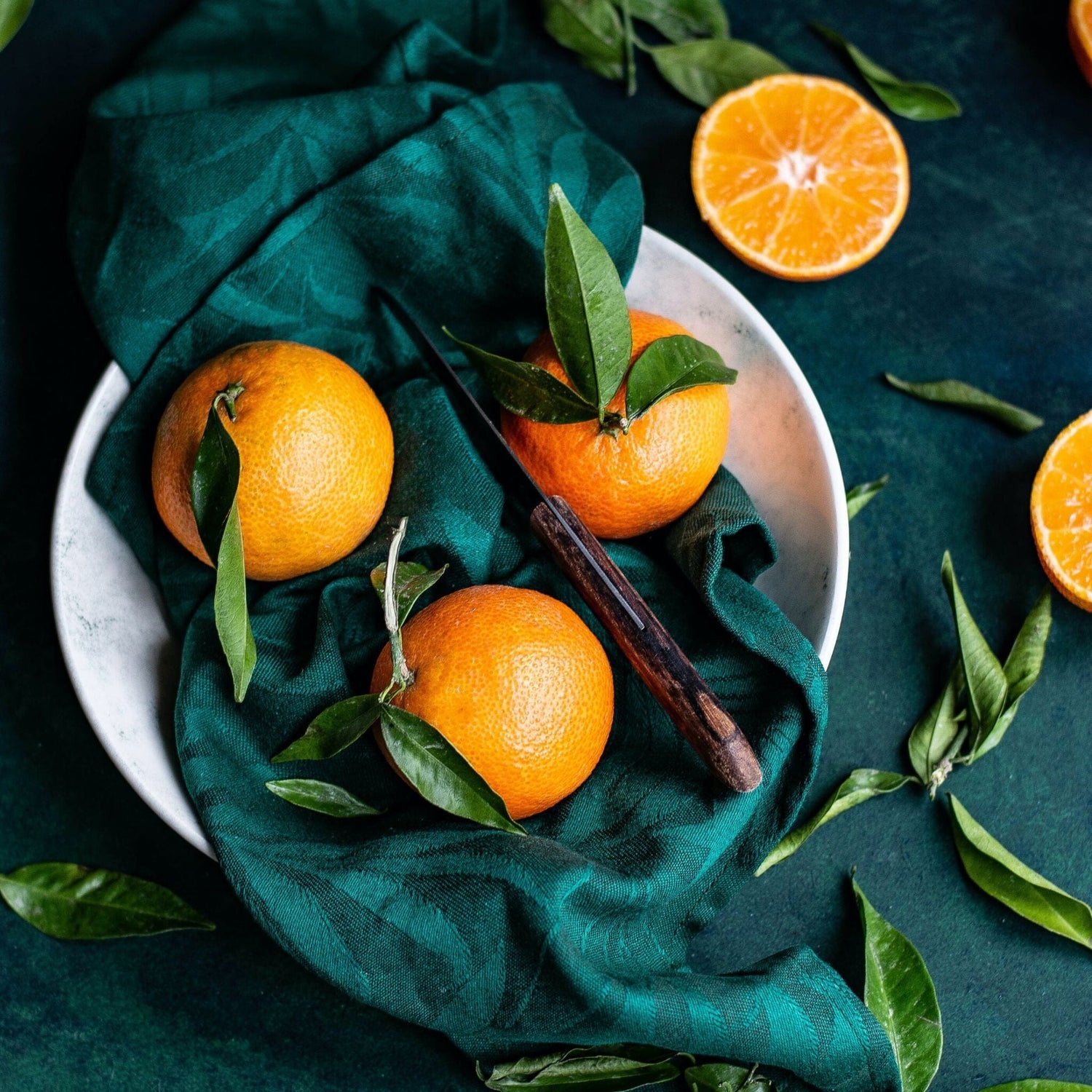 oranges and greenery in white bowl