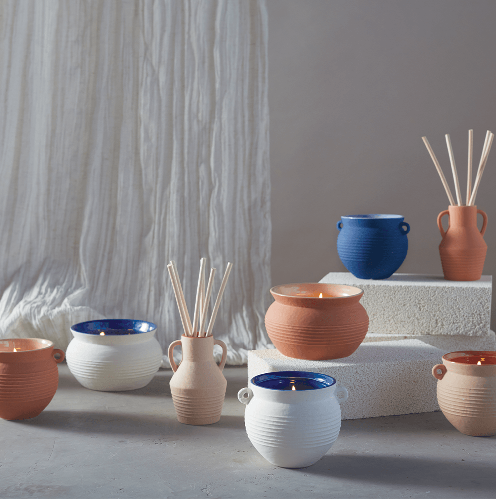 Santorini collection of diffusers and candles in traditional ceramic jars arranged to show the variety of colors and function
