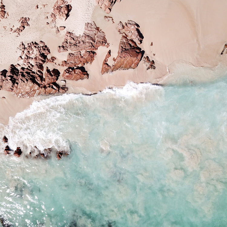 view from above of waves crashing on a rocky beach 