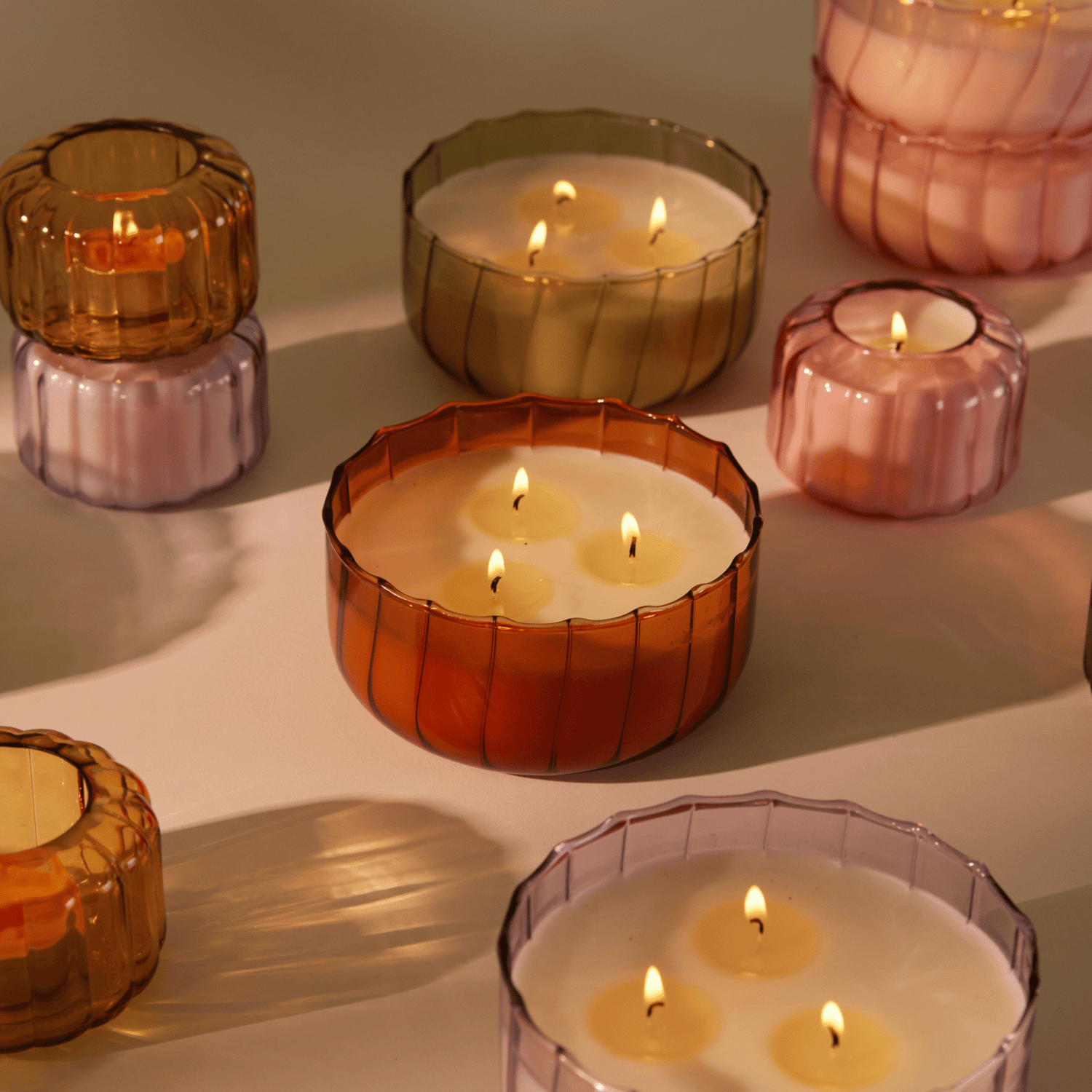 Ripple collection candles lit on a table top with deep shadow to the right