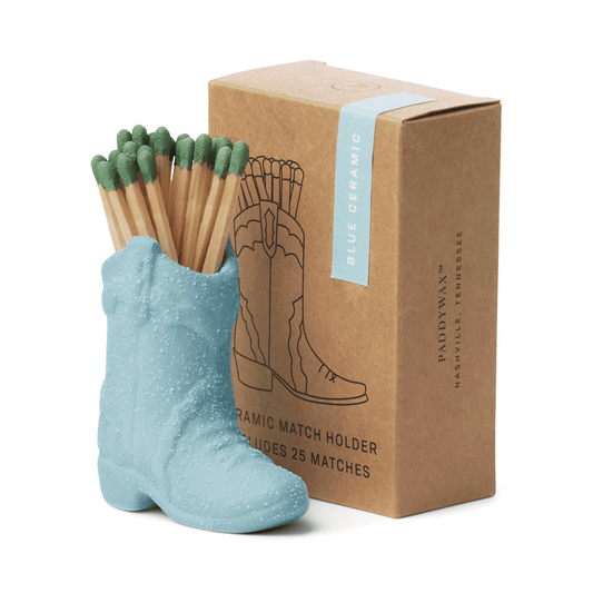 The Cowboy Boot Match Holder - Light Blue keeps green-tipped matches nearby in style. It comes in a brown box with a boot illustration—ideal as a unique ceramic accessory for vintage-inspired home decor.