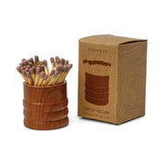 The Brown Ceramic Wood Match Holder, filled with matches and placed beside its packaging box featuring a line drawing, is an elegant complement to woodgrain candles or the Grain collection.