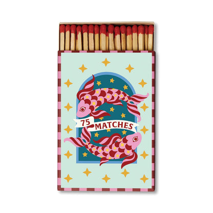 A Dopo candle lovers will appreciate the A Dopo “Koi” - 75ct Boxed Matches, featuring a colorful design of two koi fish, gold stars, and the words “75 Matches” on the front. The open box displays safety matches with red tips inside.