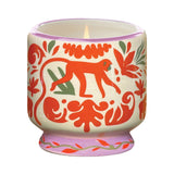 The Coconut & Amber - A Dopo 8 oz Candle comes in a lit ceramic holder with red and green animal and leaf patterns, featuring a central red monkey—perfect for fans of bold fragrance candles.