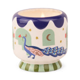 Misted Lime - A Dopo 8 oz Candle displayed in a ceramic holder adorned with blue peacock, star, and moon designs, featuring a lit hand-painted candle inside.