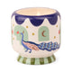 The A Dopo 8 oz Handpainted Peacock Ceramic - Misted Lime candle features a blue peacock with green arches, yellow stars, and a crescent moon in a decorative holder with a blue rim and green striped base.