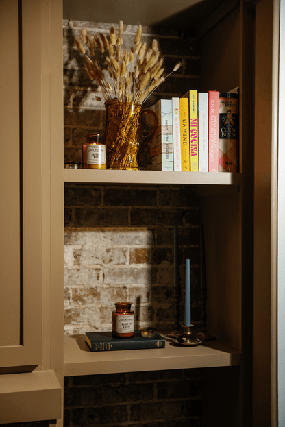 Bookshelf with books and decorative items against a brick wall.