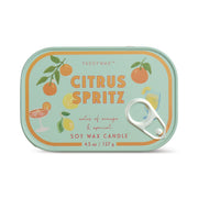 The Citrus Spritz - Bistro Tin 4.5 oz Candle features a rectangular tin with illustrations of oranges, a lemon, and citrus drinks on a mint-green background with orange and yellow accents.